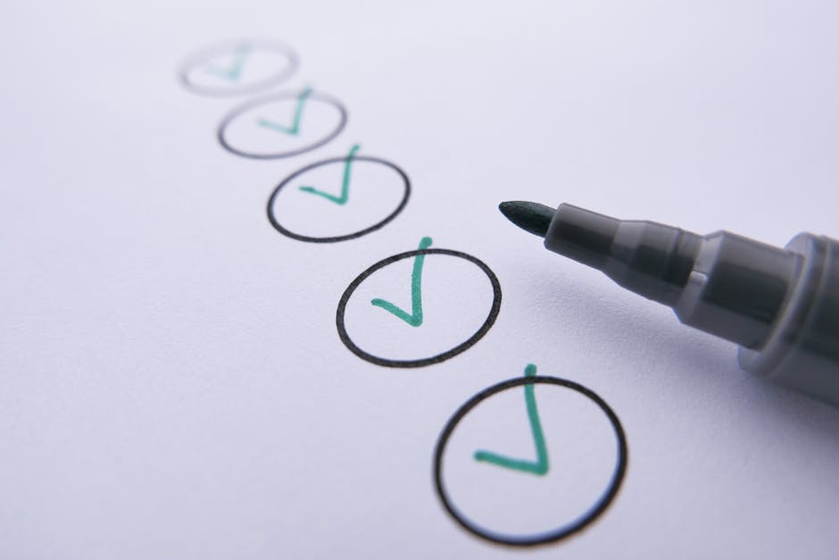 A close-up view of a white sheet of paper featuring a vertical list of five checkboxes, each outlined in black ink; four of these boxes are marked with teal checkmarks, indicating completion or approv